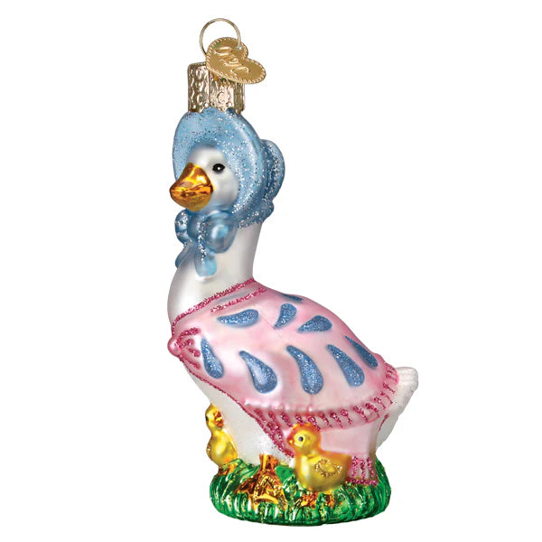 The Jemima Puddle-Duck Old World Christmas 12707 ornament showcases a delightful white goose adorned in a blue bonnet and pink cape with blue patterns. It stands on green grass with two small yellow farmyard ducks at her feet and has a gold loop for hanging.