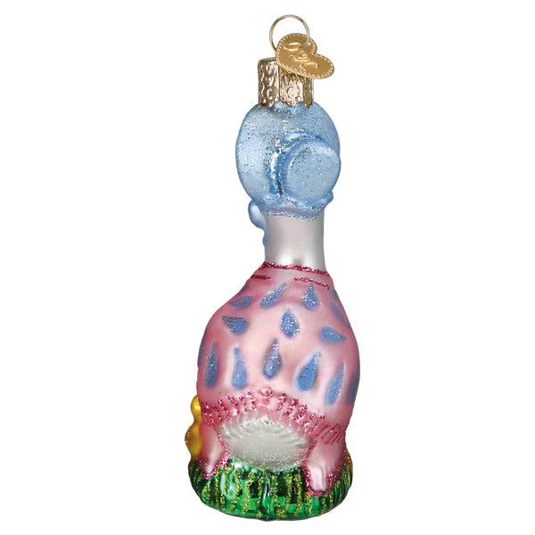 This whimsical Jemima Puddle-Duck Old World Christmas ornament showcases a colorful poodle wearing a pink jacket adorned with blue raindrop designs, seated on green grass. Its golden cap for hanging exudes the charm reminiscent of the 12707 ornament.