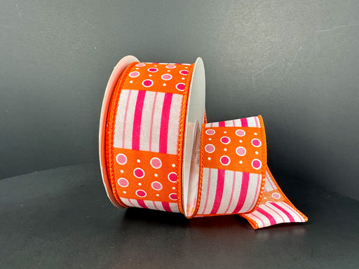 A partially unrolled roll of 1.5X10Y Fuchsia Pink Orange Jet Dot Stripes Ribbon (41510-09-19) showcases its vibrant pattern on a dark gray surface, adding a pop of color with its orange background and white polka dots and stripes to any craft or decor.