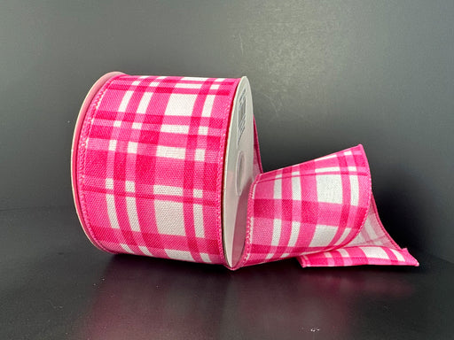 A partially unwound roll of 2.5X10Y Pink Watercolor Tuttola Plaid Ribbon 41546-40-26, featuring wired edges for easy shaping, sits elegantly against a plain dark background, showcasing its charming pattern.