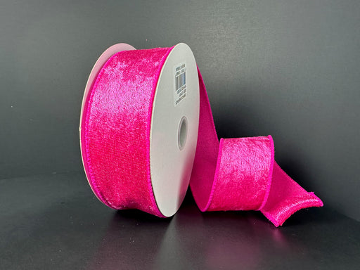 A partially unrolled 1.5X10Y Fuchsia Lush Velvet Ribbon 41549-09-28 with a vibrant, soft texture is set against a dark gray background.