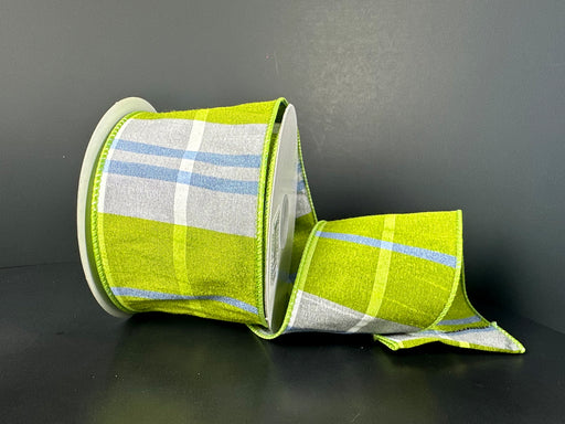 A 10-yard spool of 2.5 Kiwi Iris White Ayanna Dupioni Plaid Ribbon, with a wired green and blue plaid design, is partially unrolled on a dark surface, elegantly draping its loose end beside the white plastic spool.