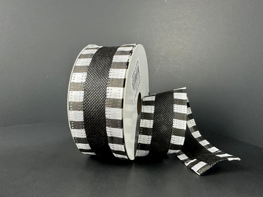 A 1.5X10Y Black Flat Breeze/Black And White Stripe Edge Ribbon, code 46521-09-21, with a wired edge is set against a dark background, partially unfurled from its circular core to reveal its checkered pattern.