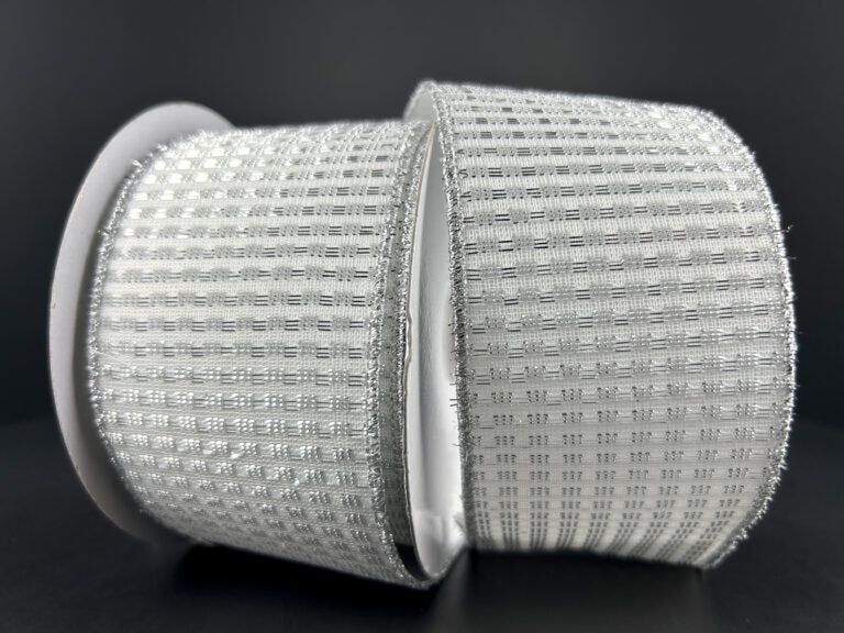 A close-up shot showcases two rolls of a 2.5"X10Y White-Silver Metallic Rishi Solid ribbon, model number 78496-40-51, with a wired design featuring a textured grid-like pattern. The rolls are positioned side by side against a dark background.