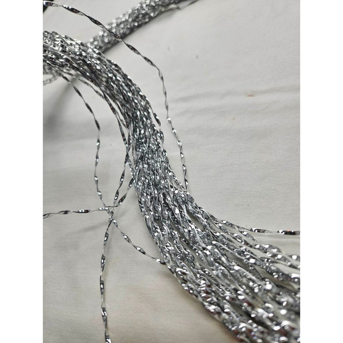 A close-up of the 39" Silver Metallic Stripe Hanging 82315-Silver showcases the shiny, twisted silver tinsel strands spread elegantly across a light surface, with its reflective, metallic appearance accentuating the silver metallic stripe.