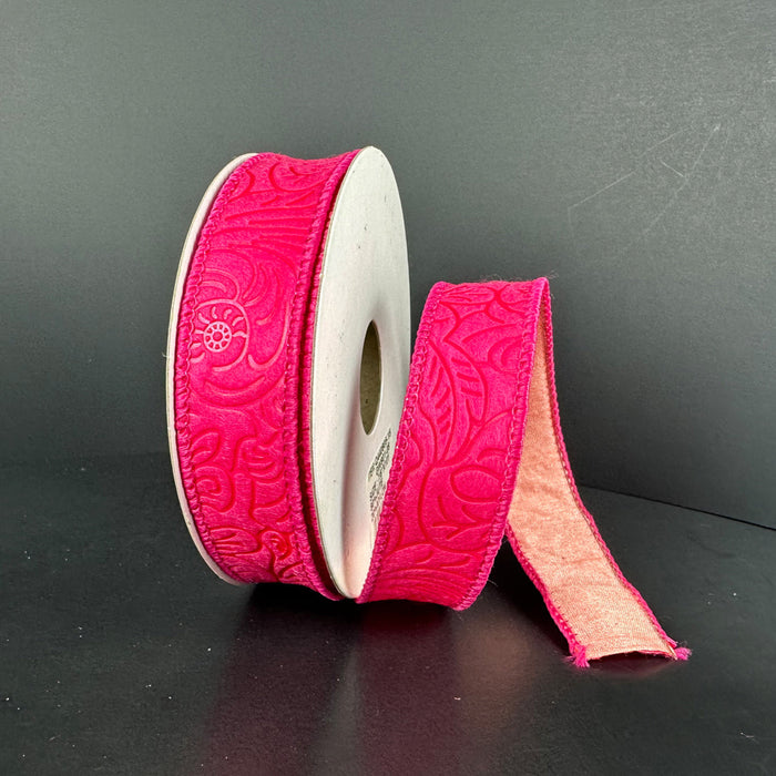 A partially unrolled 7/8X10Y Fuchsia Coral Double Sided Embossed Dupioni Ribbon, showcasing a bright pink color with an embossed floral pattern on a gray background.