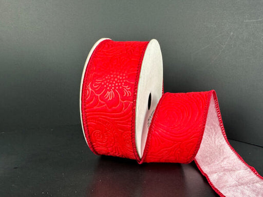 A partially unrolled spool of 1.5X10Y Double Sided Red Embossed-Pink Dupioni Ribbon (D42510-09-12) against a dark background showcases its textured, intricate floral patterns.