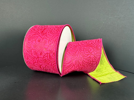 A roll of 2.5X10Y Fuchsia Kiwi Double Sided Embossed Dupioni Ribbon (D42510-40-29) with a raised floral pattern, green interior, and partially unraveled on a dark background.