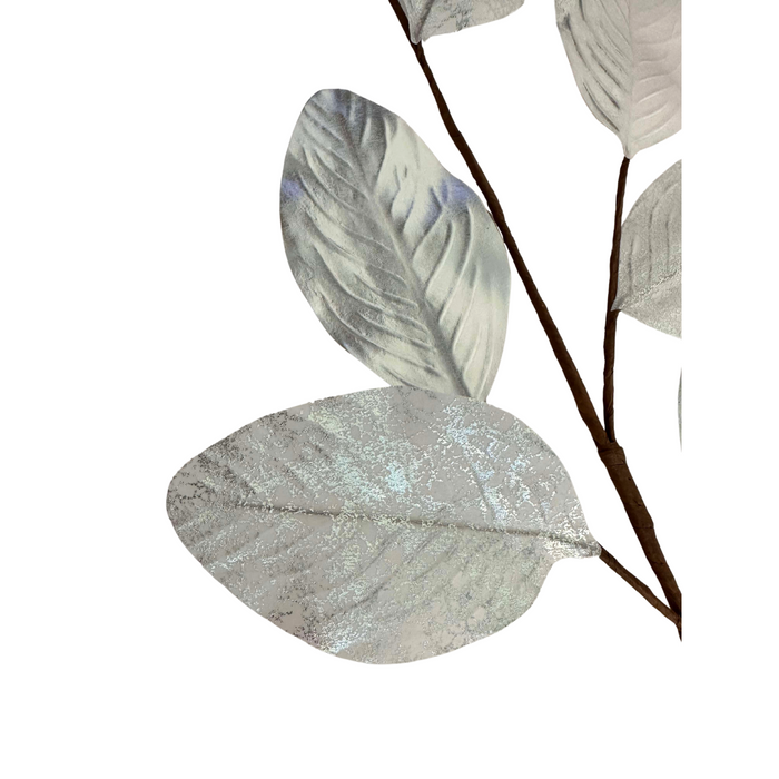 A close-up of the 27" Silver Metallic Magnolia Leaves Spray ISB78101 reveals decorative silver leaves with a shimmering texture. These metallic magnolia leaves exhibit visible veins and a captivating metallic sheen against a pristine white background.