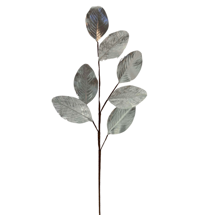 The 27" Silver Metallic Magnolia Leaves Spray ISB78101 showcases slender branches adorned with metallic magnolia leaves, arranged in an alternating pattern. These lustrous silver leaves have a textured, shiny surface that elegantly catches and reflects light against the plain white background.