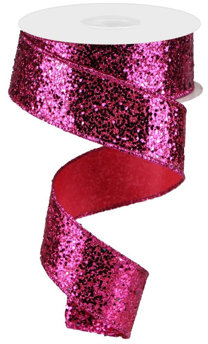 The 1.5"X10Yd Large Glitter Fuchsia RGA130007 ribbon unwinds in a loose spiral against a white background, casting a playful shimmer.