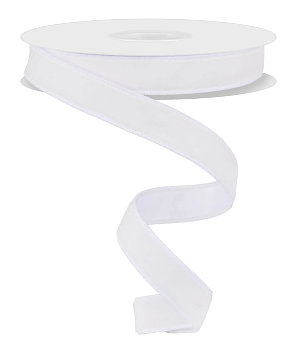 The 7/8"X10YD White Deluxe Velvet with Satin Backing Ribbon (RGE765856) is unwinding in a loose spiral. Its smooth texture and elegant appearance are highlighted against a plain white background, emphasizing its satin finish and subtle wired structure.