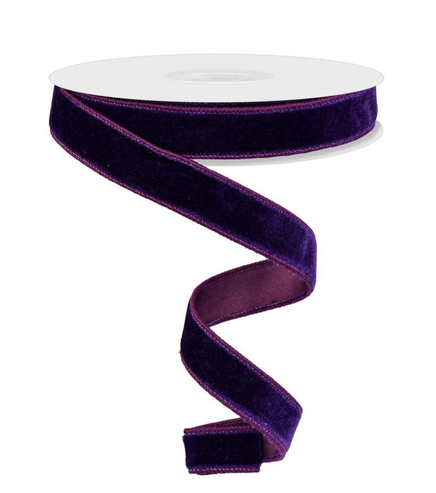 A 7/8" x 10-yard spool of Purple Deluxe Velvet With Satin Backing Ribbon (RGE765864) unrolls and hangs in a gentle spiral against a white background.