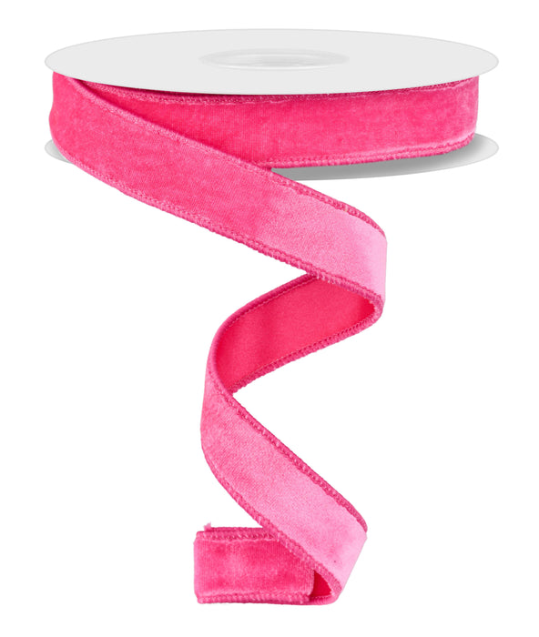 A spool of 7/8"X10Yd Deluxe Velvet/Satin Backing Hot Pink RGE765811 ribbon unfurls in a spiral pattern against a white background, weaving a captivating dance.