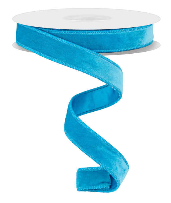 A spool of the 7/8"X10Yd Deluxe Velvet/Satin Backing Turquoise RGE765852 ribbon features a bright turquoise velvet with a wavy section elegantly cascading downward. The ribbon is partially unrolled, showcasing its smooth, vibrant texture against a plain white background.